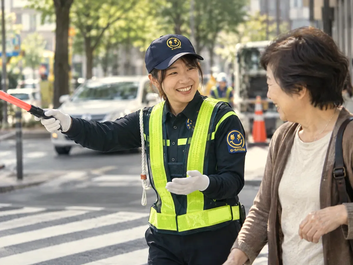 横断歩道で歩行者を笑顔で案内する警備スタッフ